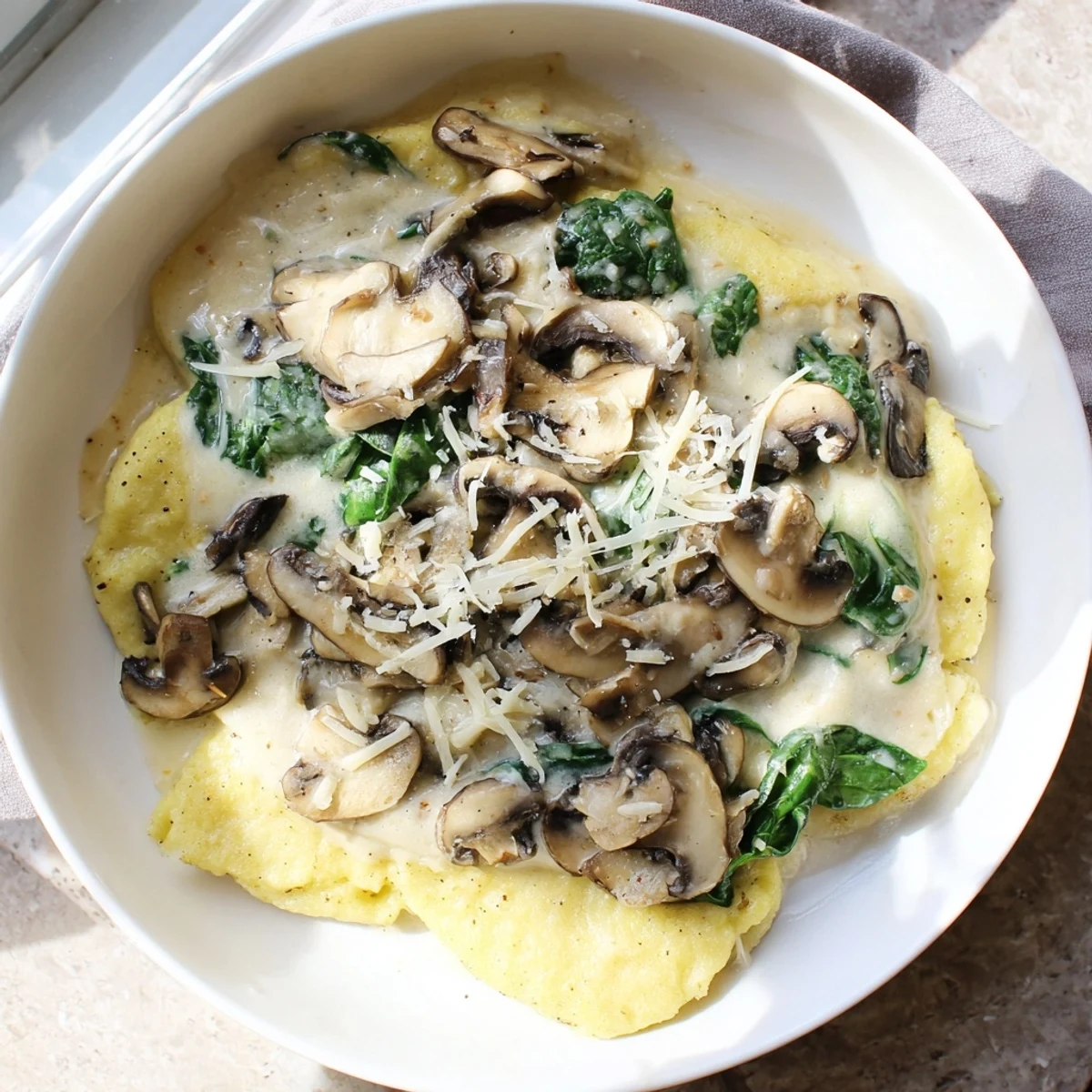 One-Dish Creamy Mushroom and Spinach Gnocchi, a comforting vegetarian pasta dish with melted Parmesan cheese.