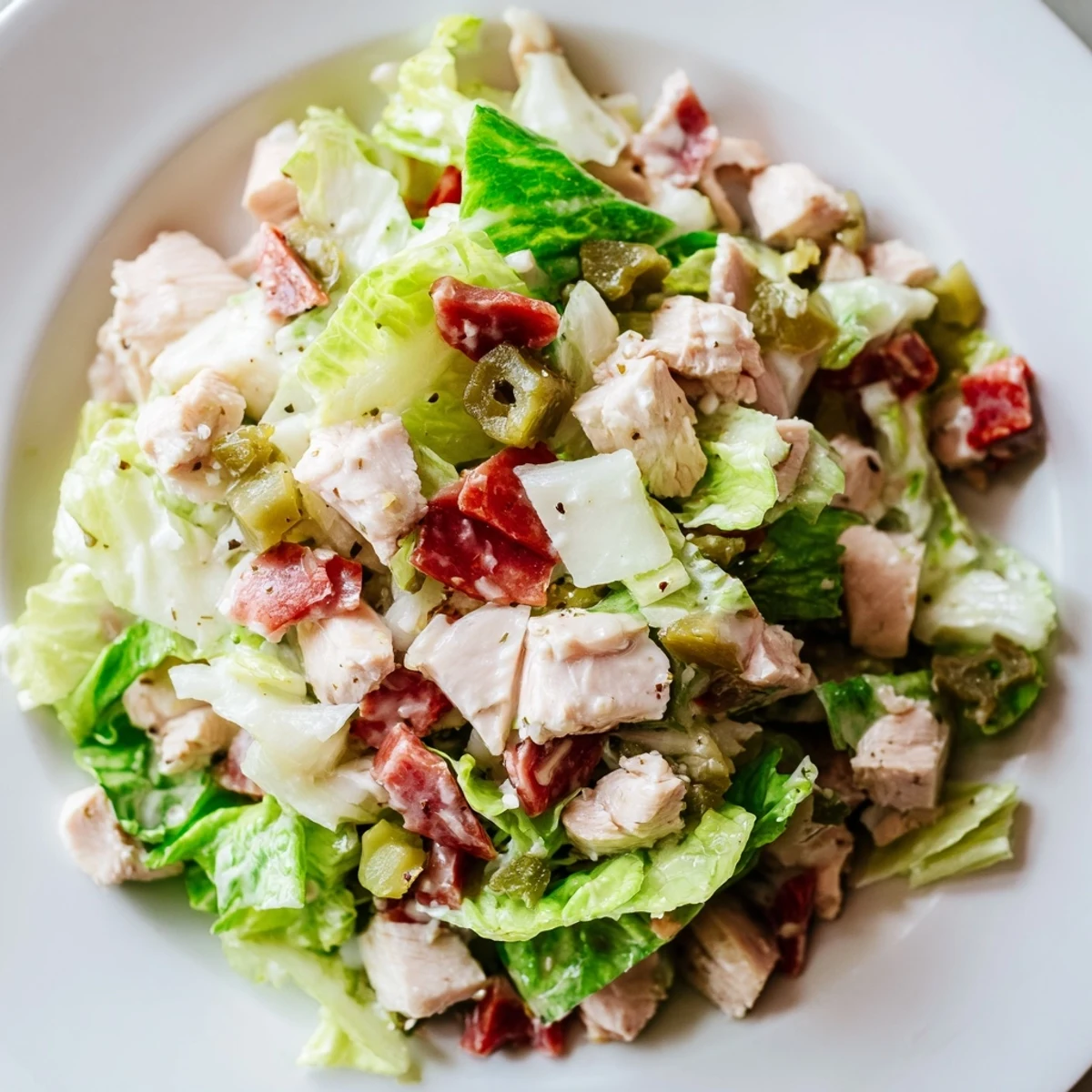 Close-up of Italian Deli Chopped Chicken Salad showing diced chicken, red onion, cucumbers, and glossy dressing glistening.
