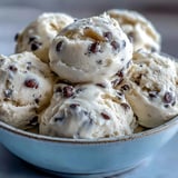 A chilled bowl of Greek Yogurt Cookie Dough, topped with extra chocolate chips, sits beside a glass of milk.