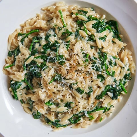 Creamy Spinach Orzo, a comforting one-pan meal with glistening Parmesan and fresh green spinach.
