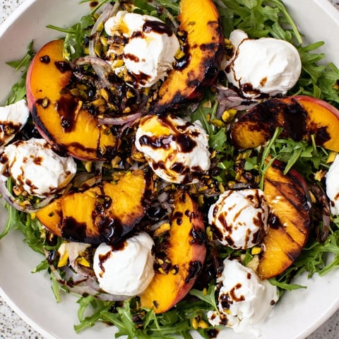 Grilled peach salad with charred peaches, creamy burrata, and fresh arugula, a summer delight.