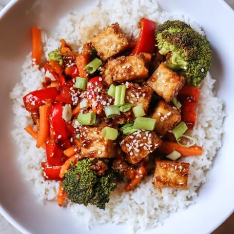This close-up showcases flavorful Honey Garlic Tofu Bowls; imagine tender tofu alongside colorful, cooked vegetables.