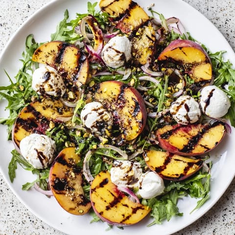 Flavorful grilled peach salad drizzled with balsamic glaze, garnished with toasted nuts, ready to eat.