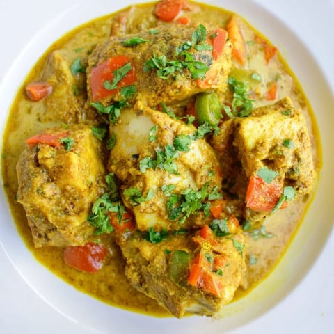A steaming bowl of Bahraini Fish Curry, garnished with fresh cilantro, ready to eat.