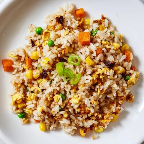 Aromatic black garlic fried rice topped with scallions, a sunny-side-up egg, and savory sesame notes.  