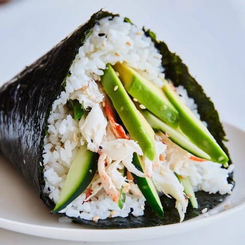 Close-up of a homemade Sushi Rice Hand Roll, showing layered textures of rice, fresh vegetables, and shredded crab, ready to dip in soy sauce.