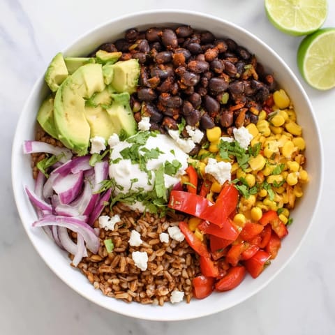 Brown Rice Burrito Bowl featuring warm seasoned rice, hearty black beans, and fresh vegetables topped with creamy sour cream and cilantro.  