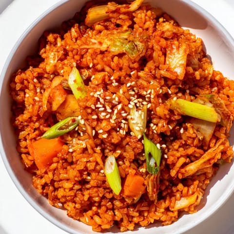 Sizzling Kimchi Fried Rice in a black skillet with carrots and green onions.  