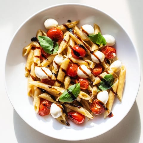 Summer-inspired Caprese Salad Pasta tossed with torn basil leaves, served as a vibrant main dish.