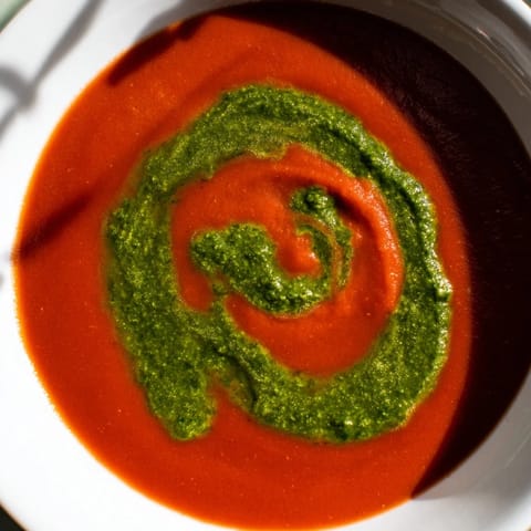 A rich, velvety tomato soup topped with a vibrant swirl of homemade basil pesto for extra flavor.  