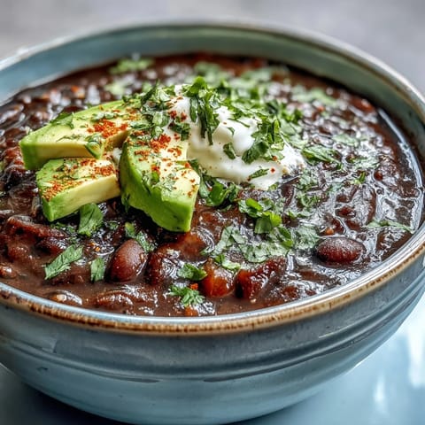 A pot of Black Bean Soup simmering with spices, diced vegetables, and steam rising from the broth.