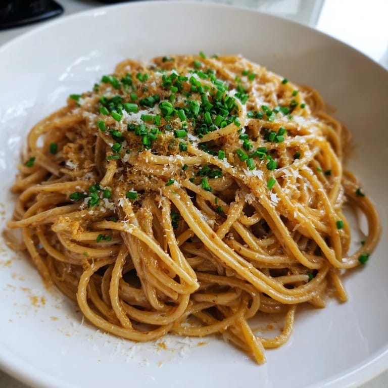 Velvety Miso Butter Pasta glistening with olive oil and Parmesan, garnished with fresh chives, a flavorful delight.